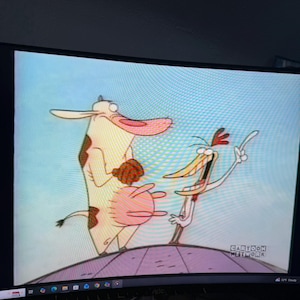 Peut inclure: Capture d'écran d'un dessin animé avec une vache et un poulet. La vache est principalement blanche avec des taches marron et un grand pis rose. Le poulet est grand et mince avec un long bec et fait signe. Le logo Cartoon Network est en bas à droite.