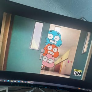 Puede incluir: Una captura de pantalla de una pantalla de televisión que muestra una escena de dibujos animados del programa "El increíble mundo de Gumball". Los personajes Gumball, Darwin y Anais están asomándose desde detrás de una puerta. El texto "NUEVO EPISODIO" y el logotipo de Cartoon Network son visibles en la esquina inferior derecha de la pantalla.