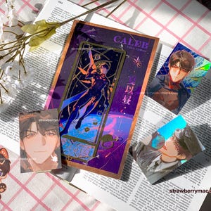 May include: A collection of anime-style merchandise including a rectangular bookmark with a gold frame, three rectangular trading cards featuring character portraits, and a small die-cut sticker of a character with cat ears.