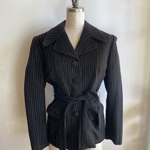 May include: A black and white striped blazer with a belt. The blazer has a notched collar, long sleeves, and a button closure. The belt is black and has a buckle.