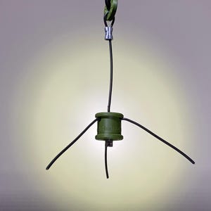 May include: A green, cylindrical device with the word "Hammock" printed on it. The device has four black wires extending from it, three of which are connected to a silver connector at the top.