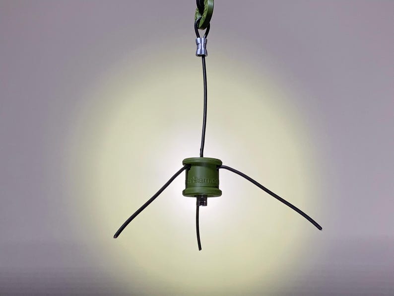 May include: A green, cylindrical device with the word "Hammock" printed on it. The device has four black wires extending from it, three of which are connected to a silver connector at the top.
