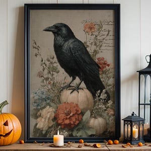 May include: A rustic wooden table displays Halloween decor. A framed print of a raven, carved pumpkins, black lanterns with lit candles, and a black vase with fall foliage create a festive autumn scene. A carved jack-o'-lantern sits on the table.