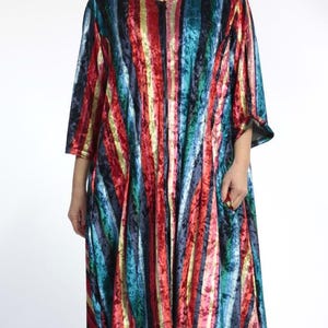 May include: A vibrant, striped tunic dress in red, blue, and yellow. The dress features a round neckline, three-quarter sleeves, and an asymmetrical hem. The fabric has a soft, velvet-like texture. The dress is a striking piece of clothing.