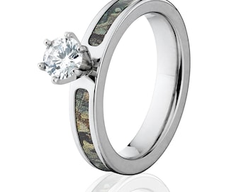 Op de afbeelding: Een zilveren ring met een camouflageband en een enkele ronde diamant in een kraalbezetting.