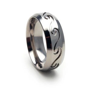 May include: A silver ring with a wave design carved into the band.