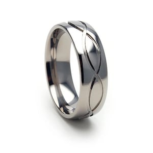 May include: A silver titanium ring with a unique, intricate design featuring a series of overlapping curves.