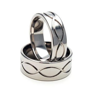 May include: Two silver titanium rings with an intricate Celtic knot design. The rings are stacked on top of each other.