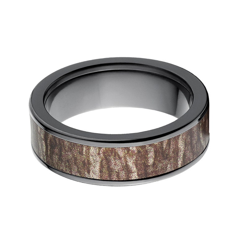 May include: A black ceramic ring with a brown wood inlay. The ring has a polished finish and a wide band.