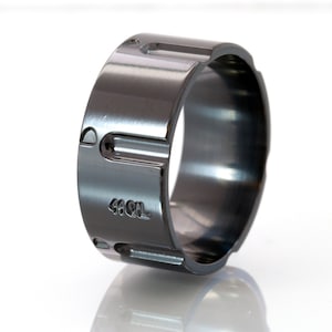 May include: A black metal ring with a textured surface and the inscription "44 CAL" on the side.