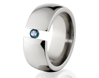 May include: A silver titanium ring with a blue gemstone set in a channel setting.