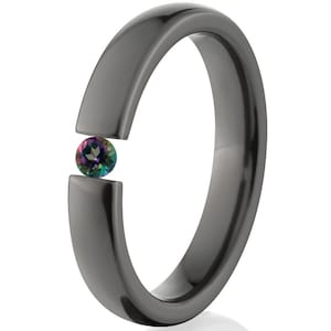 May include: A dark gray ring with a gap in the band, showcasing a small, round, multi-colored gemstone. The ring has a smooth, polished finish, and the gemstone appears to be a vibrant mix of colors.