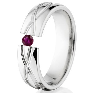 May include: A silver wedding band with a ruby gemstone set in the center. The band has a unique design with a braided pattern.