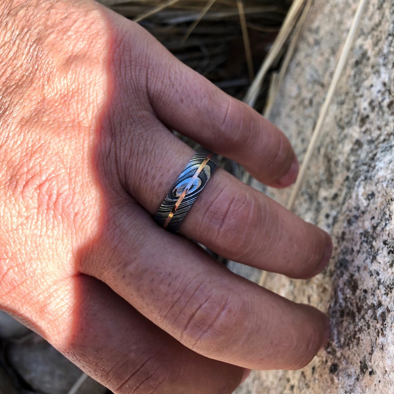 May include: A silver and gold patterned ring with a thin gold band.