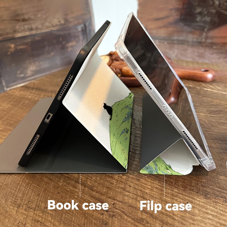 May include: Two tablet cases, a book case and a flip case, are displayed. The book case is black with a white interior featuring a black cat on a green hill design. The flip case is clear. The text "Book case" and "Filp case" are at the bottom.
