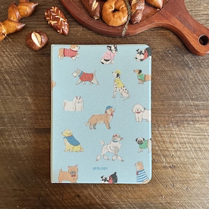 Puede incluir: Una tabla de cortar azul con un patrón repetido de perros que llevan ropa. Los perros están en varias poses y llevan diferentes atuendos. El texto "UPOLOGY" está impreso en el centro inferior de la tabla.