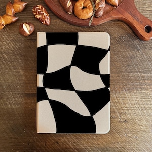May include: A rectangular case with a black and beige checkered pattern. The case is on a wooden surface, with various baked goods in the background, including pretzels and bagels.
