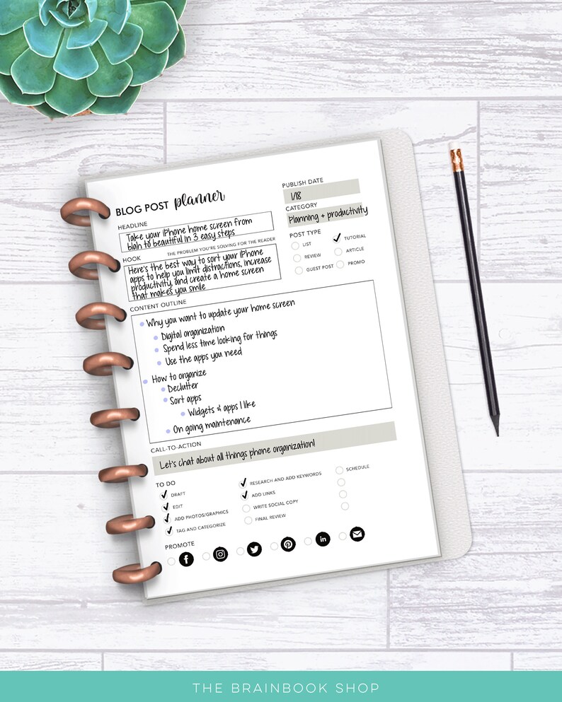 May include: A blog post planner notebook with a white cover and copper-colored binding. The planner includes sections for headlines, outlines, and to-do lists. A pencil rests on the right side. The text on the planner reads "BLOG POST planner".