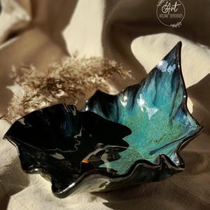 May include: A dark blue and green ceramic bowl with a wavy edge. The bowl is glazed and has a shiny finish.