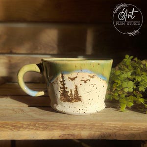 Taza de cerámica hecha a mano con motivos de bosque y montaña