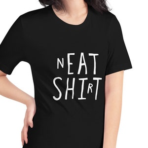 May include: A black t-shirt with the words "NEAT SHIRT" printed in white on the front.