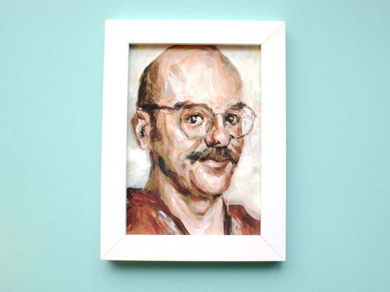 May include: A framed painting of a man with a mustache and glasses. The painting is done in a realistic style with a focus on the man's face. The background is a light cream color.