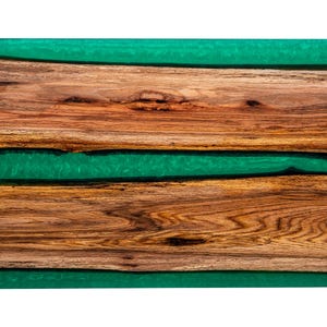 May include: A wooden serving board with three layers of wood and two layers of green epoxy resin.