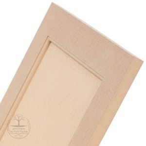 May include: A close-up of a light wood cabinet door with a raised panel design. The door has a simple, clean look and is made of high-quality materials.
