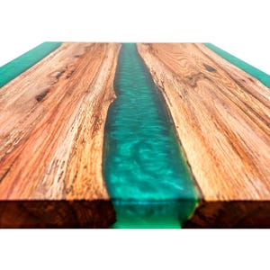 May include: Close-up of a wooden table top with a green epoxy resin river running down the center.