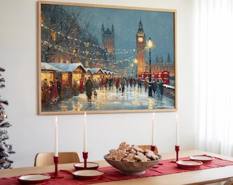 May include: A framed print of a winter scene in London, featuring the Houses of Parliament and Big Ben. The image shows a Christmas market with people, red double-decker buses, and streetlights. A wooden table is set with candles, plates, and gingerbread cookies.