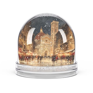 Peut inclure: Un globe de neige avec une base argentée et un dôme en verre transparent. À l'intérieur, une peinture à l'aquarelle détaillée représente une scène de ville européenne avec une cathédrale, des bâtiments et des personnes. La scène se déroule pendant une chute de neige.