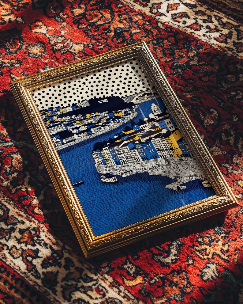 K&ouml;nnte beinhalten: Ein gerahmter Kunstdruck mit einer detaillierten Illustration einer Stadtlandschaft mit Fluss, Br&uuml;cke und Geb&auml;uden. Das Kunstwerk befindet sich in einem goldfarbenen Rahmen und liegt auf einem roten gemusterten Teppich.
