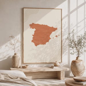 May include: A rectangular wall art print featuring a terracotta-colored silhouette of the Iberian Peninsula map centered on a cream background. The map is filled with fine, wavy horizontal lines, and similar wavy line patterns appear in the top left and bottom right corners of the print.