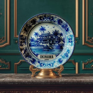 May include: A decorative plate featuring a blue and white illustration of Okinawa, Japan, with a detailed landscape scene. The plate is displayed on a gold-colored stand, showcasing a traditional Japanese design.