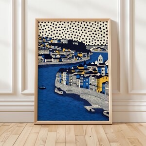 K&ouml;nnte beinhalten: Ein gerahmter Kunstdruck, der eine Stadtlandschaft mit einem Fluss zeigt. Das Kunstwerk zeigt Geb&auml;ude in Blau-, Gelb- und Wei&szlig;t&ouml;nen, mit einer Br&uuml;cke und Booten. Der Himmel ist ein Muster aus schwarzen Punkten auf cremefarbenem Hintergrund.