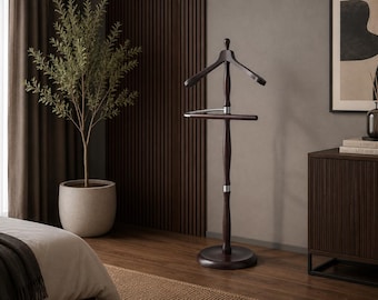 May include: A dark brown wooden valet stand featuring a contoured coat hanger at the top, a horizontal bar for trousers, and a central vertical post supported by a circular base, accented with silver-toned metal connectors between the wooden sections.