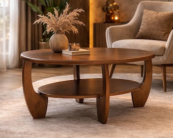 May include: A round wooden coffee table with a smooth brown finish, featuring a lower oval shelf and three curved legs that extend upward to support the circular tabletop. The table has a warm, polished wood grain texture throughout its surface.
