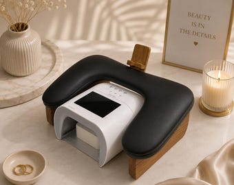 May include: A white and black nail lamp with a built-in armrest and wooden accents. The lamp has a digital display and is designed for professional nail care. A small gold-framed sign reads "BEAUTY IS IN THE DETAILS".