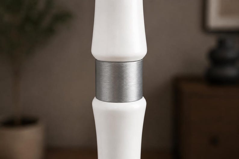 May include: A vertical lamp post section featuring two smooth, glossy white cylindrical components separated by a central brushed silver metal band. The design consists of a symmetrical arrangement with the metallic accent positioned between the white parts.