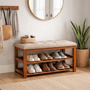 Könnte beinhalten: Ein Schuhregal aus Holz mit zwei Regalen, das verschiedene Schuhpaare enthält. Auf dem Regal befindet sich eine gepolsterte Sitzbank. Eine Garderobe mit Mänteln und Accessoires hängt an der Wand. Ein runder Spiegel und Topfpflanzen vervollständigen den Eingangsbereich.