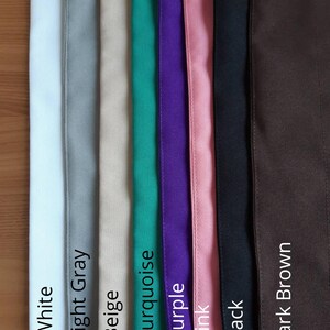 May include: A vertical display of fabric swatches in various colors, including white, light gray, beige, turquoise, purple, pink, black, and dark brown. Each swatch is labeled with its corresponding color name in white text.