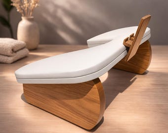 May include: A modern footrest with a white cushioned top and a wooden base. The footrest has a curved design and is made of light-colored wood. The design is minimalist and elegant, suitable for home decor.