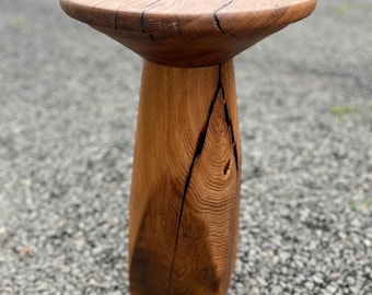 May include: A handcrafted wooden side table with a round top and a unique, geometric base. The natural wood grain and cracks add character to this rustic, decorative piece. The table is approximately 20 inches tall.