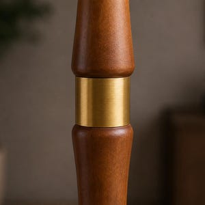 May include: A vertical wooden pole segment featuring a smooth, medium-brown finish with a prominent, cylindrical brushed brass metal band connecting two rounded, turned wood sections in a symmetrical, stacked design.
