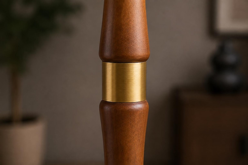 May include: A vertical wooden pole segment featuring a smooth, medium-brown finish with a prominent, cylindrical brushed brass metal band connecting two rounded, turned wood sections in a symmetrical, stacked design.