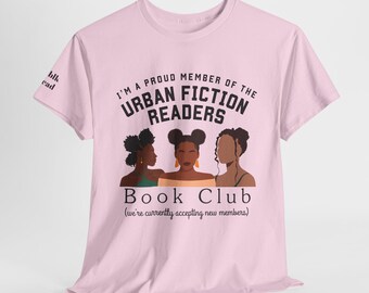 Könnte beinhalten: Ein hellrosa T-Shirt mit kurzen Ärmeln, das eine Grafik von drei Personen und den Text I'M A PROUD MEMBER OF THE URBAN FICTION READERS BOOK CLUB (we're currently accepting new members) zeigt. Auf dem Ärmel steht der Text blk read.