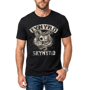 Pode incluir: T-shirt preto com gola redonda com um gráfico de caveira e cobra e o texto "LYNYRD SKYNYRD". O design é em estilo vintage. A pessoa está usando jeans azuis. A camiseta tem um corte clássico.