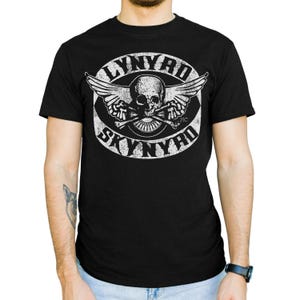 May include: Black t-shirt featuring a distressed white graphic of a skull with wings and crossed bones, encircled by the words "LYNYRD SKYNYRD". The design is centered on the chest of the shirt.