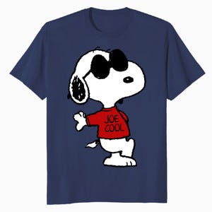 May include: A navy blue short-sleeved t-shirt featuring a graphic of the cartoon character Snoopy wearing black sunglasses and a red shirt with the text JOE COOL printed in black. The character is white with black ears and a black nose.