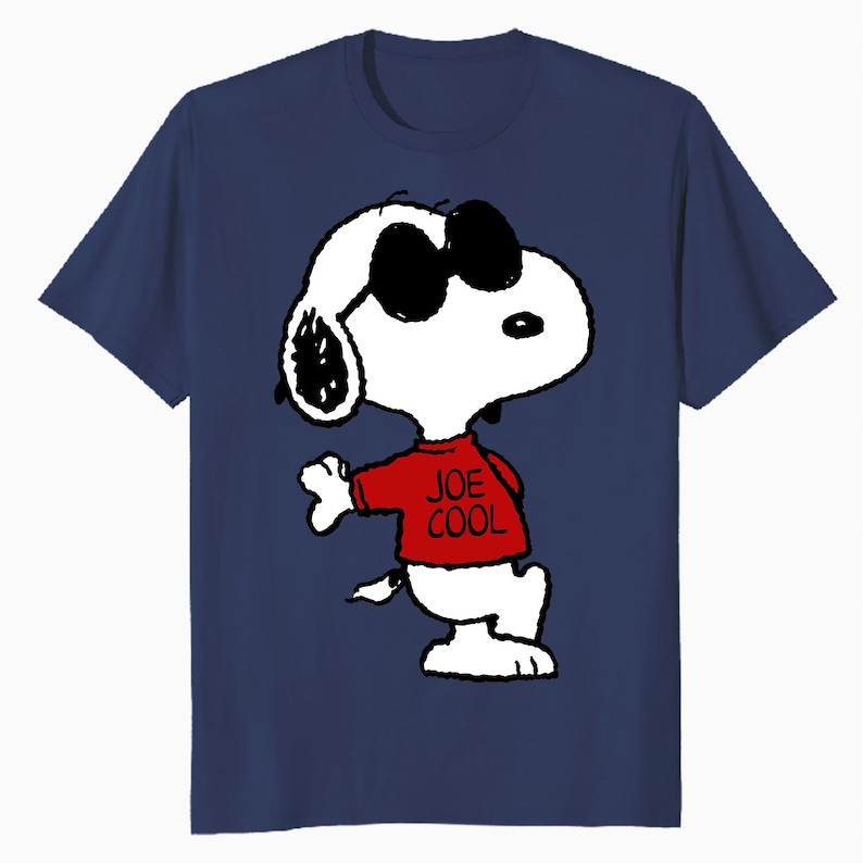 May include: A navy blue short-sleeved t-shirt featuring a graphic of the cartoon character Snoopy wearing black sunglasses and a red shirt with the text JOE COOL printed in black. The character is white with black ears and a black nose.